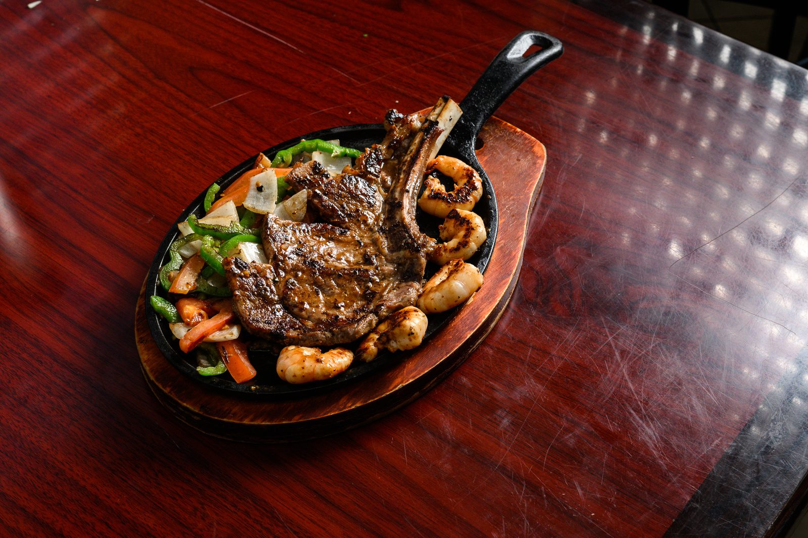 Steak and shrimp skillet on a wooden board